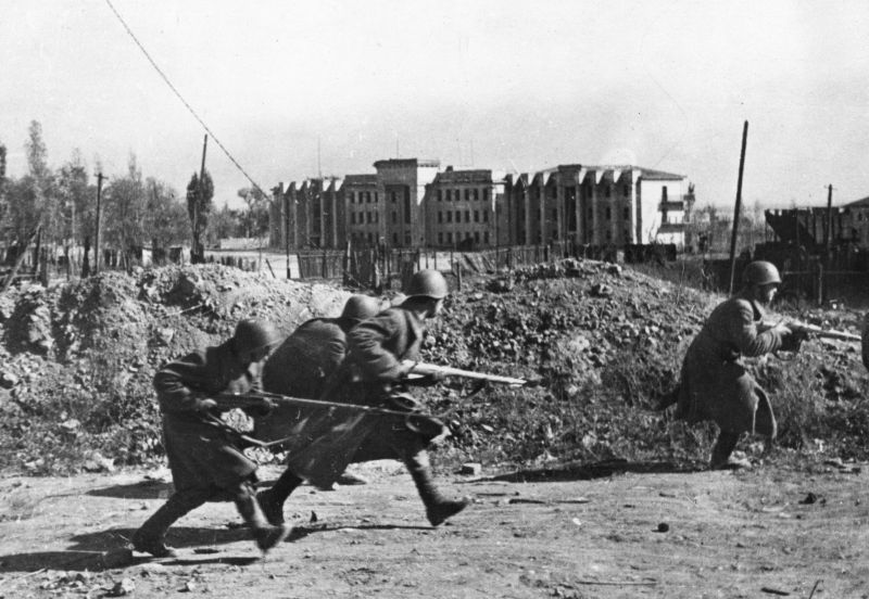 Красноармейцы меняют позицию во время уличных боев в Сталинграде. На заднем плане видно здание клуба инженерно-технических работников или дом техники ЗКО.