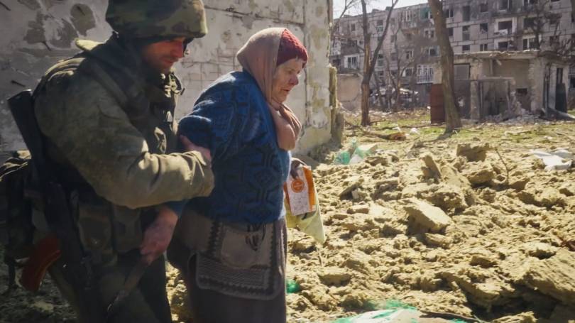 Боец выводит бабушку из под обстрела